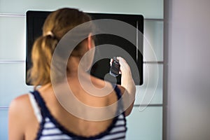 Young woman at home watching TV, changing channel