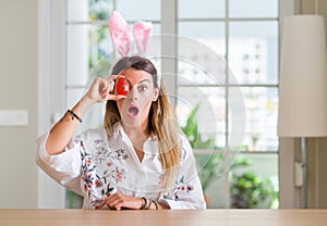 Young woman at home wearing easter rabbit ears scared in shock with a surprise face, afraid and excited with fear expression