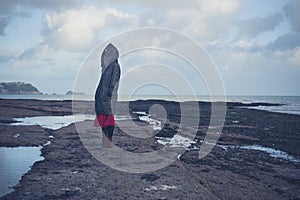 Young woman in hooded coat walking on beach