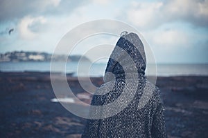 Young woman in hooded coat walking on beach