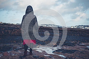 Young woman in hooded coat walking on beach