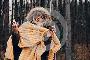 A young woman in a hooded jacket and a plaid feels happy after swimming in cold water in autumn