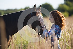 Young woman and horse in the meadow at summer evening