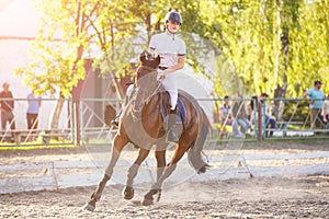 Young woman horseback riding on show jumping course in equestrian competition