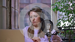 Young woman host wearing headphones talks on live radio Spbas