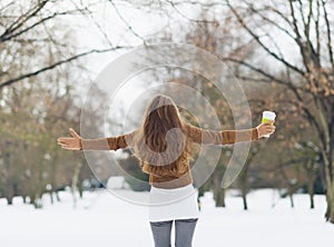 Young woman with hot beverage in winter park