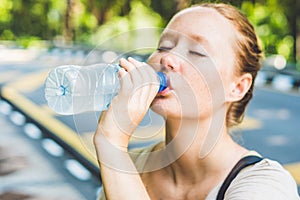 Young woman in hot weather drinks water from a bottle