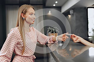 Young woman hotel guest receiving key card from receptionist