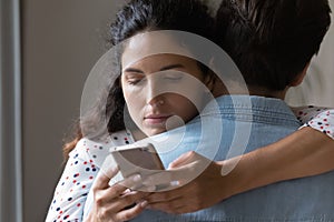 Young woman hug husband cheating online on cellphone