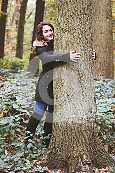Young woman hugging a tree in forest- nature lover and tree hugger