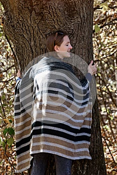 Young woman hugging a tree. Unity with nature, autumn forest