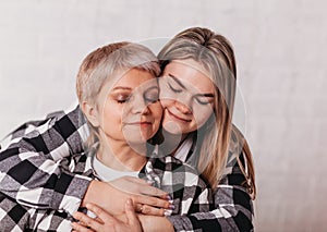 Young woman hugs her elderly mother with tenderness