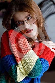 A young woman hugs herself in a warm sweater, anxiety and worry