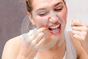 Young woman hurting herself in using dental floss for hygiene