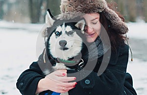 Young woman with husky dog in the winter park.