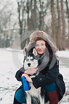 Young woman with husky dog in the winter park.