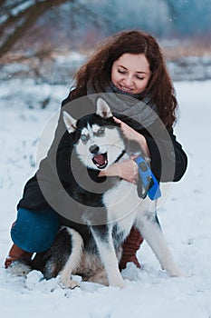 Young woman with husky dog in the winter park