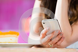 Young woman in ice cream parlor with phone texting