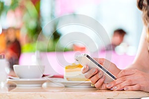 Young woman in ice cream parlor with phone texting