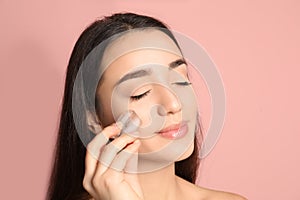 Young woman with ice cube on color background.