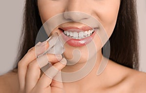 Young woman with ice cube on light background