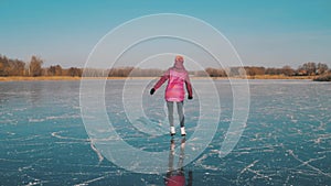 Young woman ice skating on a frozen lake on a freezing winter day. People, winter sport and leisure concept.