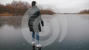 Young woman ice skating on a frozen lake on a freezing winter day. People, winter sport and leisure concept.