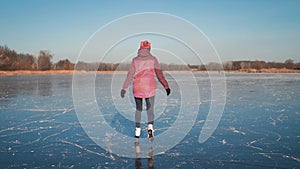 Young woman ice skating on a frozen lake on a freezing winter day. People, winter sport and leisure concept.