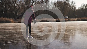 Young woman ice skating on a frozen lake on a freezing winter day. People, winter sport and leisure concept.