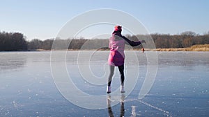 Young woman ice skating on a frozen lake on a freezing winter day. People, winter sport and leisure concept.