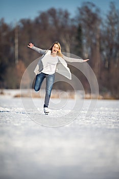 Young woman ice skating outdoors on a pond on a freezing winter