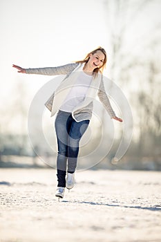 Young woman ice skating outdoors on a pond on a freezing winter