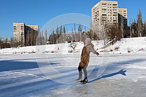 Young woman ice skating outdoors on a pond in winter day