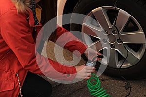 Young woman inflating car tire on street, closeup