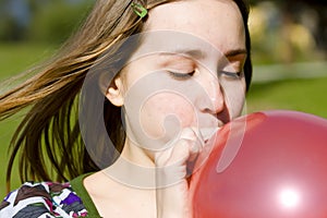 Young woman inflating red balloon