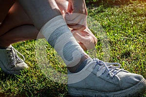 The young woman injured the tendons on her leg during an outdoor jogging. Self-bandaging. Running leg injury accident woman