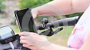 young woman installs a smartphone on the handlebars of bicycle in special mount for navigation,for live broadcasting