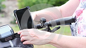 young woman installs a smartphone on the handlebars of bicycle in special mount for navigation,for live broadcasting