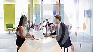 Young woman interviewing a guest in a studio for a podcast