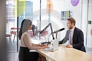 Young woman interviewing a guest in a studio for a podcast photo