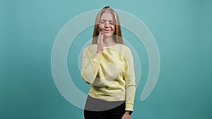 Young woman isolated on turquoise background suffering from severe toothache.