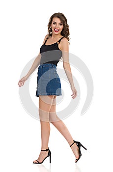 Young Woman In Jeans Mini Skirt And High Heels Is Walking And Talking. Side View