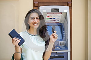 Young woman in jeans short using an automated teller machine