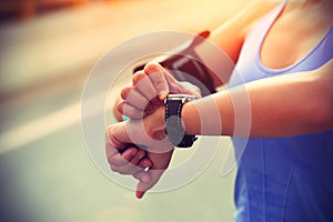 Young woman jogger ready to run set and looking at sports smart watch