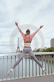 Young woman jogger in sport clothes in Paris, France jumping