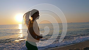 A young woman jogging along the sandy sea beach.