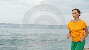 A young woman jogging along the sandy sea beach.