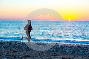 Young Woman jogging on Beach along Sea Surf at Sunrise