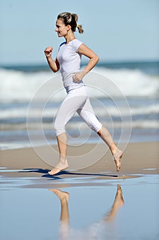 Young woman jogging on the beach in summer