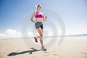 Young woman jogging on the beach in summer day. Athlete runner exercising actively in sunny day